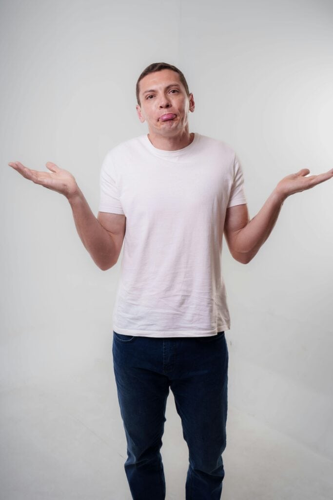 Man shrugging his shoulders with a neutral expression in studio